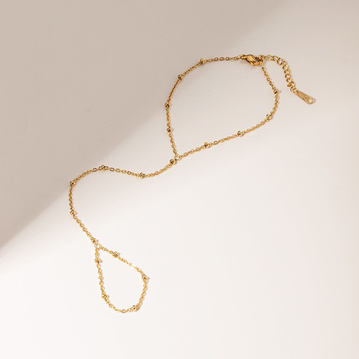 Detaljerad produktvy av det guldpläterade rostfria stål pärlchain armbandet, som framhäver låset och fin hantverk.