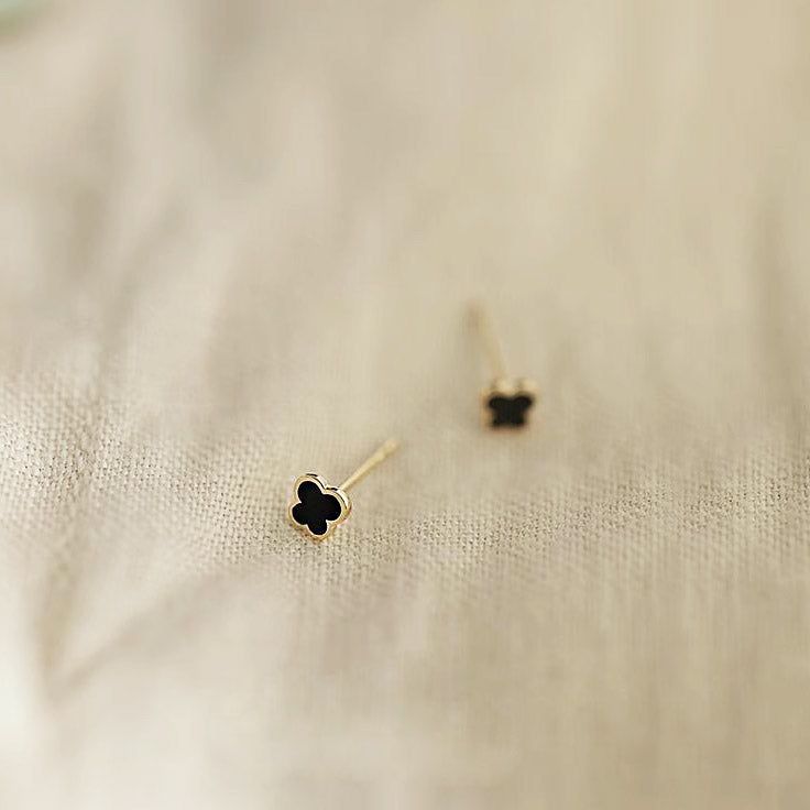 Un primer plano de los pendientes de botón de plata esterlina 925 chapados en oro de 14K, con un pequeño diseño de mariposa con esmalte negro.