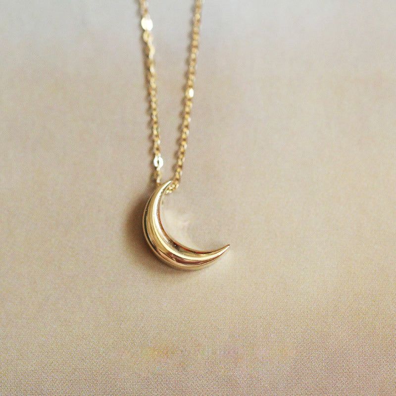 Scatto dettagliato in studio della collana in argento sterling 925 con un delicato pendente a forma di piccola luna dorata su uno sfondo neutro.