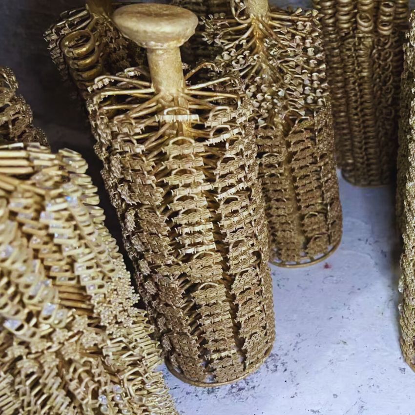 Une vue détaillée d'un arbre de coulée de bijoux, présentant plusieurs pièces de couleur or avec des designs complexes, fraîchement coulées et prêtes pour la prochaine étape de production chez JR Fashion Accessories.
