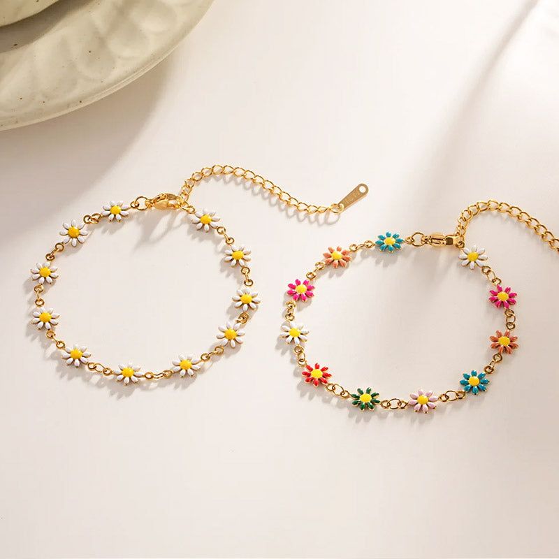 Een paar Koreaanse stijl roestvrijstalen armbanden met emaille madeliefjes charms, één met witte bloemen en de andere met multicolore bloemen.