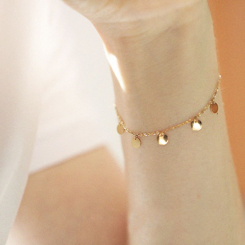 Close-up van een 925 sterling zilveren armband uit de set van 5, met vergulding en delicate hangende mini-sequinschijven.