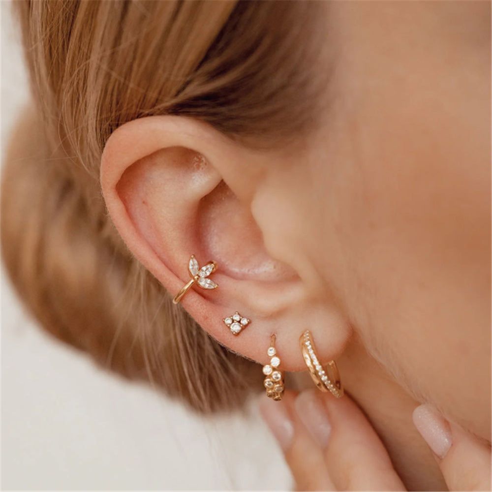 Una collezione straordinaria di orecchini a clip in argento sterling 925 con zirconia minimalista, che mostrano intricati design di libellule e fiori su uno sfondo bianco.