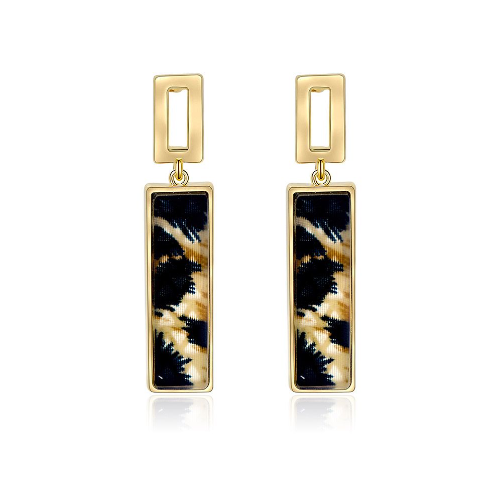Un par de pendientes de stud con estampado de leopardo hechos de latón chapado en oro, con un distintivo inserto de patrón negro y dorado, mostrado sobre un fondo blanco.