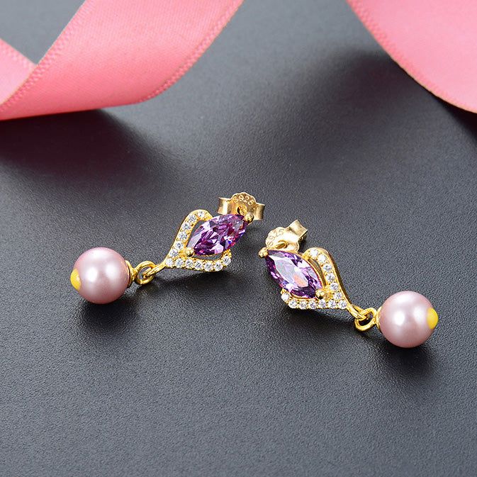 Primo piano degli orecchini in argento sterling 925, che mostrano la brillante zirconia cristallo viola e la lucente perla a goccia su una montatura color oro.