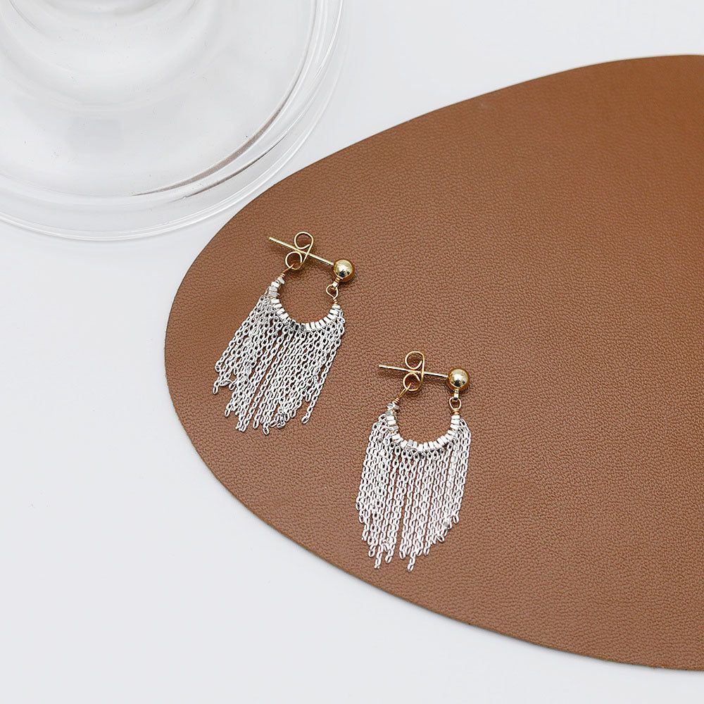 Une paire de boucles d'oreilles à franges en argent plaqué élégantes avec un design de tige et de boule en or, mettant en valeur les délicates franges en chaîne argentée.