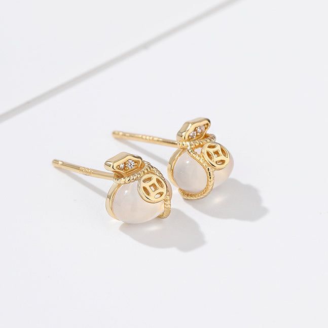 Un primo piano degli orecchini a bottone a forma di sacchetto di denaro fortunato in argento sterling 925, con una brillante placcatura in oro e accentuati da delicate perle bianche e diamanti.