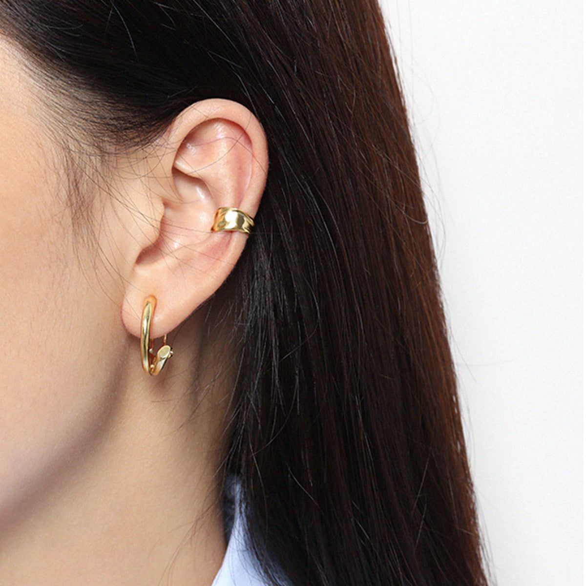 Una modella che indossa l'orecchino a cerchio in oro non forato minimalista, mostrando la sua vestibilità elegante e il design sull'orecchio. Realizzato in argento sterling 925.