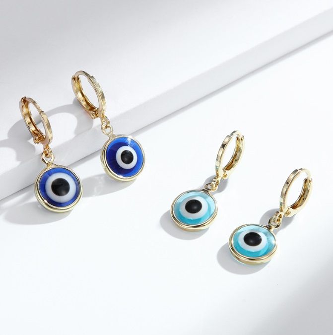 Une paire de petites boucles d'oreilles œil maléfique en laiton plaqué or, mettant en avant le design complexe en émail et en cristal.