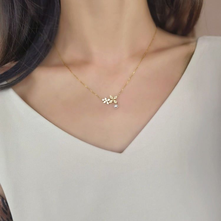 Un primo piano di una collana in argento sterling 925 con finitura dorata, caratterizzata da un pendente a foglia di trifoglio con zirconia e una perla centrale, rappresentante il set all'ingrosso.