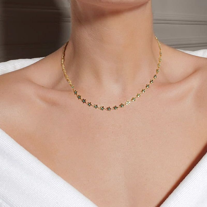 Un modello che indossa la collana in acciaio inossidabile con charm a forma di fiore di camomilla, mostrando il suo design delicato su una maglietta bianca.