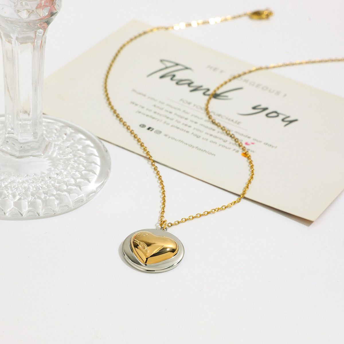 Groothandel roestvrijstalen twee-tone hart hanger ketting met een gouden en zilveren afwerking, weergegeven op een neutrale achtergrond.