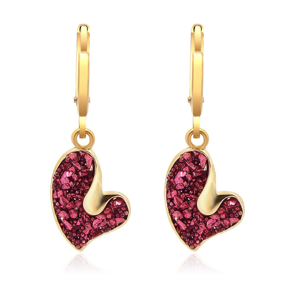Un gros plan des boucles d'oreilles en forme de cœur scintillant rouge et rose, montrant le crochet français plaqué or et le pendentif en cœur en acrylique rose scintillant.