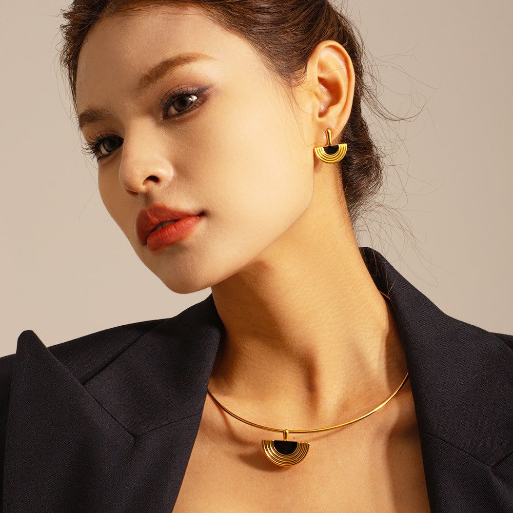 En modell som visar det eleganta 18K guldpläterade egyptiska fläktformade hängsmycket och matchande örhängen, som framhäver dess sofistikerade design.