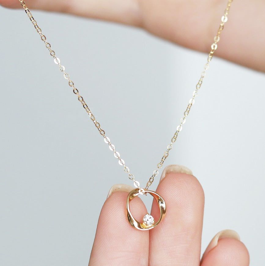 Gros plan sur un collier pendentif en argent sterling 925 avec un pendentif en forme de Mobius et une pierre centrale en zircon cubique, mettant en valeur son design élégant.
