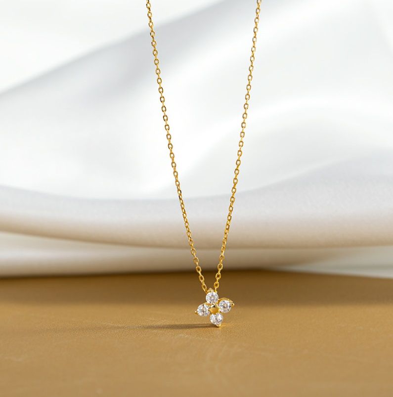 Un impresionante collar de trébol de hoja de plata esterlina 925 en acabado dorado, con un colgante de trébol de cuatro hojas engastado con brillantes piedras de circonio cúbico blanco.