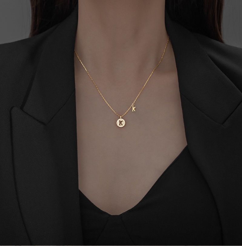 A close-up of the 925 Sterling Silver Gold Plated Initial Coin Necklace, showcasing the detailed 'K' pendant on a delicate gold chain.