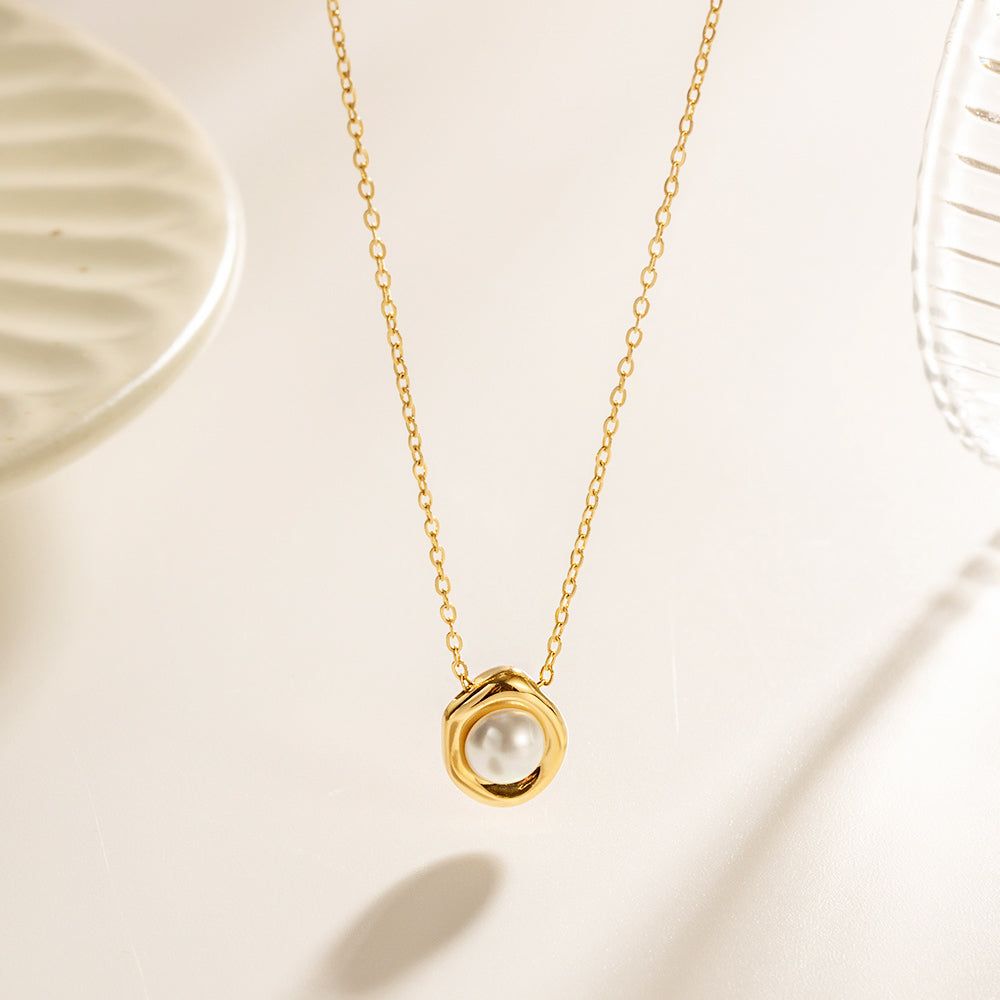 Elegant guldpläterat rostfritt stål halsband med en unik oregelbunden pärlhängsmycke, på en ren vit bakgrund.
