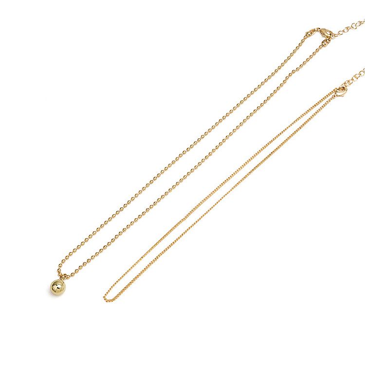 Close-up van de dubbele ketting gelaagde mini bal ketting, met de sferische hanger en delicate kettingdetails.