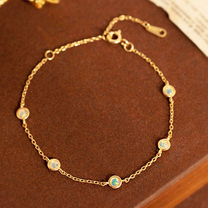 Un primer plano de la pulsera de plata esterlina 925 con chapado en oro de 18K, mostrando las cinco hermosas piedras de ópalo engastadas en bisel sobre un fondo blanco limpio.