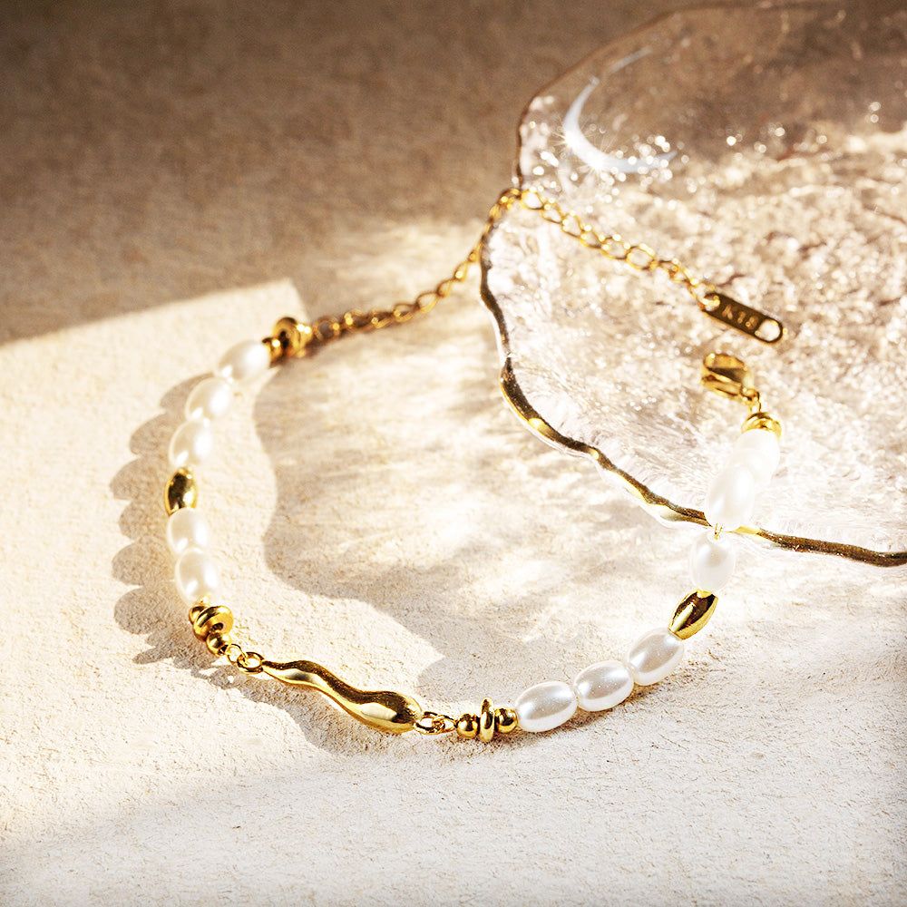 Ein Set aus fünf vintage Perlenarmbändern aus Edelstahl in Goldfarbe, elegant für die Produktpräsentation angeordnet.