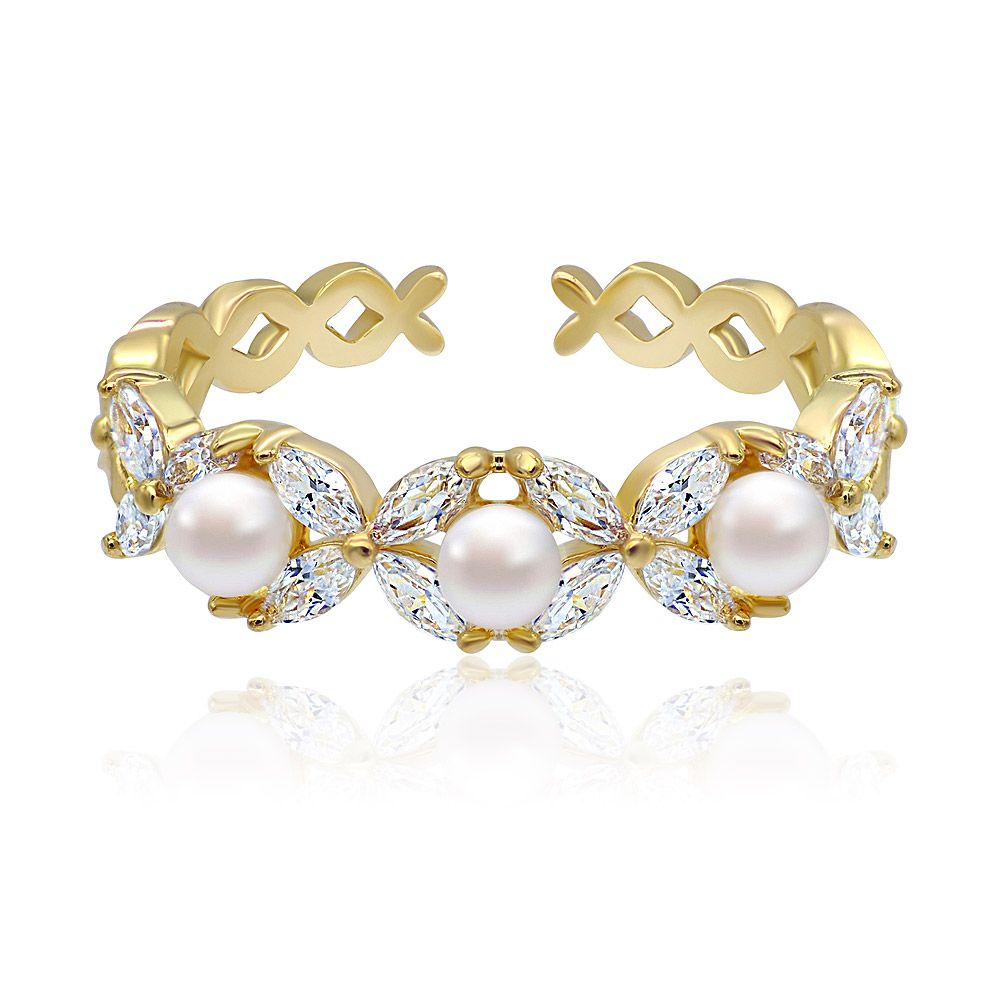 Un primo piano dell'anello Triple White Pearl e CZ, che mette in mostra le sue tre brillanti perle bianche e le scintillanti pietre di zirconia cubica incastonate su una fascia placcata in oro lucido.