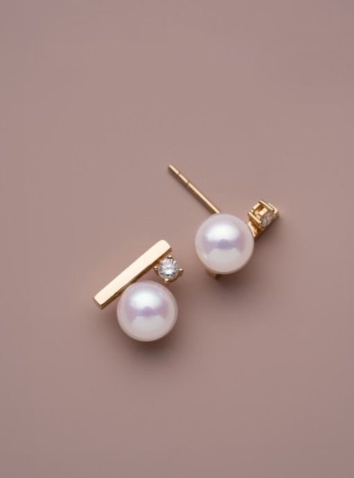 Un paio di eleganti orecchini a perla in argento sterling 925 con placcatura in oro, che mostrano un design classico perfetto per collezioni di gioielli all'ingrosso.