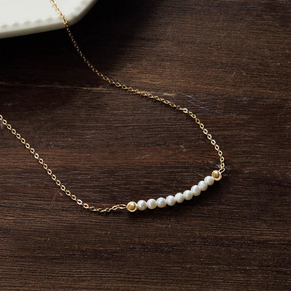 A set of 5 gold-plated clavicle chain necklaces with freshwater pearls, elegantly displayed to showcase their simple and aesthetic design.