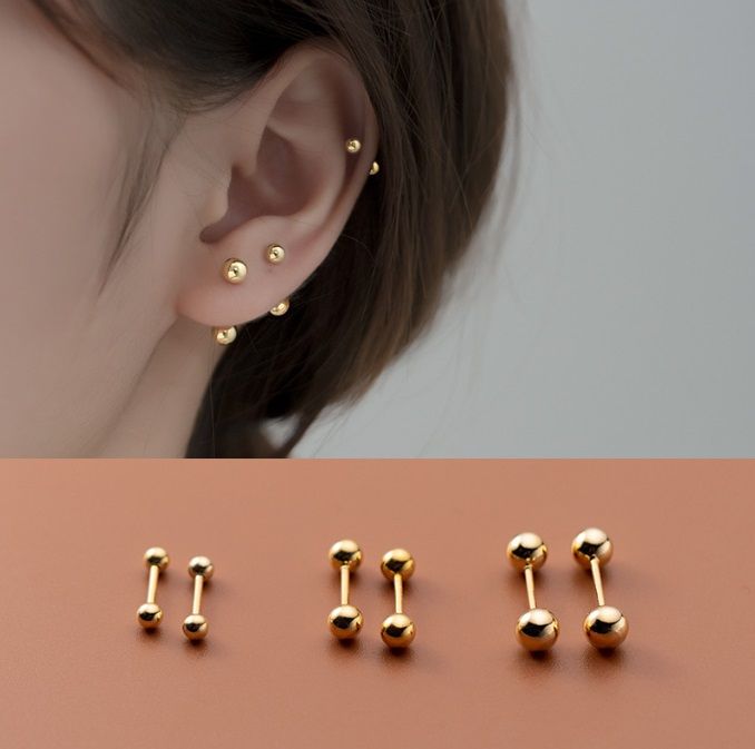 Primo piano degli orecchini a perno a doppia sfera in argento sterling 925 con finitura dorata lucida, che mostrano il classico design a barbell con doppia sfera.