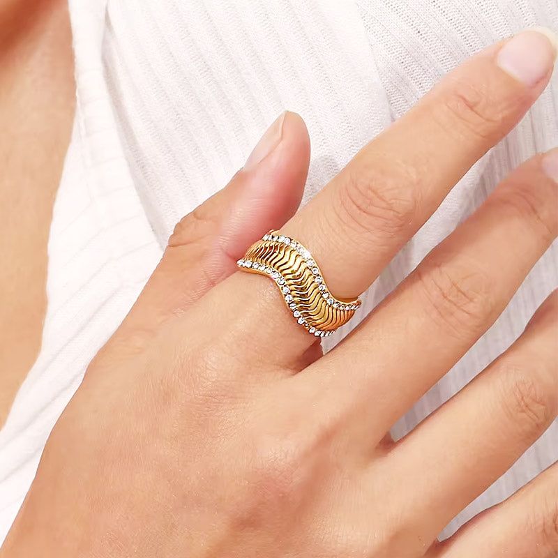 Une magnifique bague en acier inoxydable plaqué or de l'ensemble de 5 pièces, présentant un design ondulé unique avec des accents en zircon scintillants.