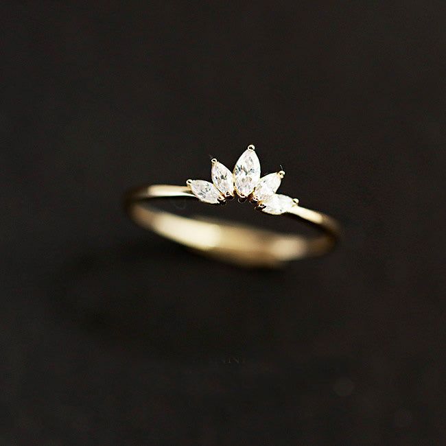 5つのきらめく透明な宝石を持つ花の蓮の花びらの形にデザインされた金メッキの925スターリングシルバーのリングのクローズアップ。