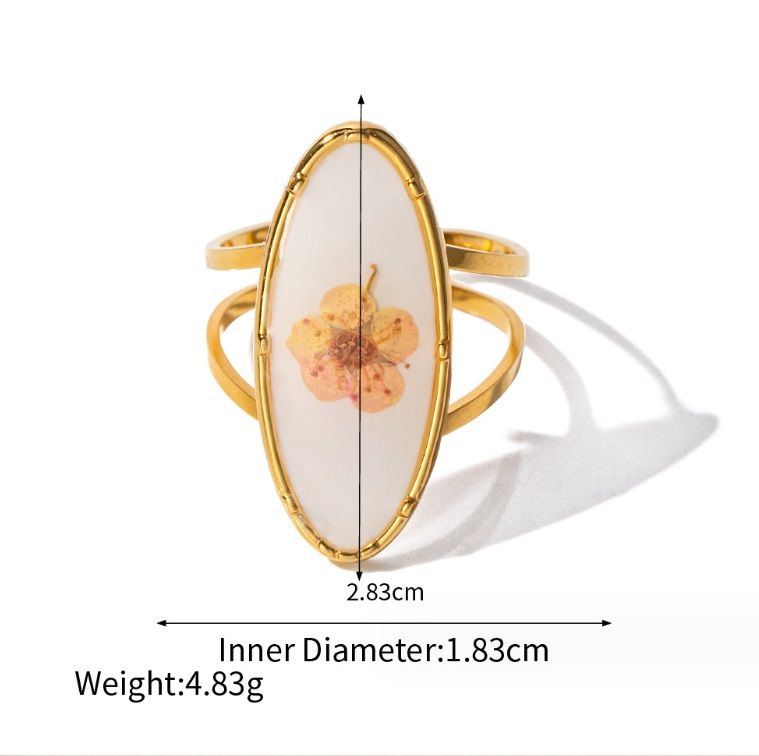 Close-up do anel de flor em aço inoxidável JRS-007 da JR Fashion, apresentando uma delicada camada de ouro e uma pedra branca central em um design floral.