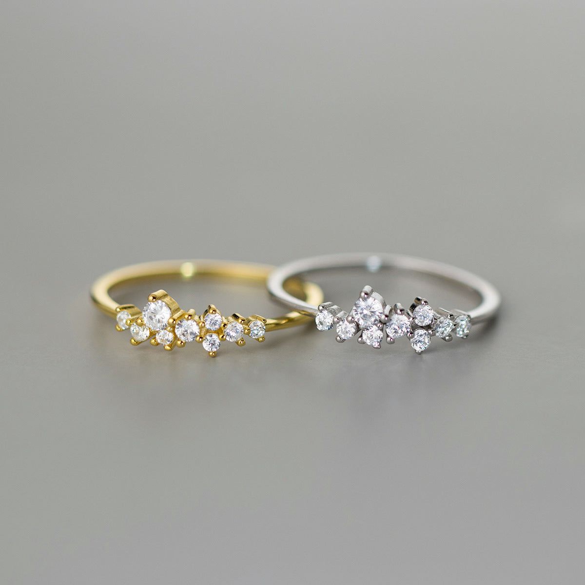 Un gros plan du set de bagues étoilées minimalistes en argent sterling 925 avec zirconias irréguliers, présentant à la fois les options en argent et plaquées or avec des pierres zirconias scintillantes.