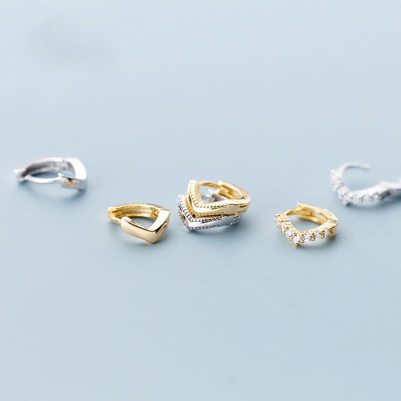 Uma coleção de Brincos Huggie Helix Hoop em Forma de V Pequenos de Prata Esterlina, exibidos em acabamentos dourados e prateados e em vários estilos.