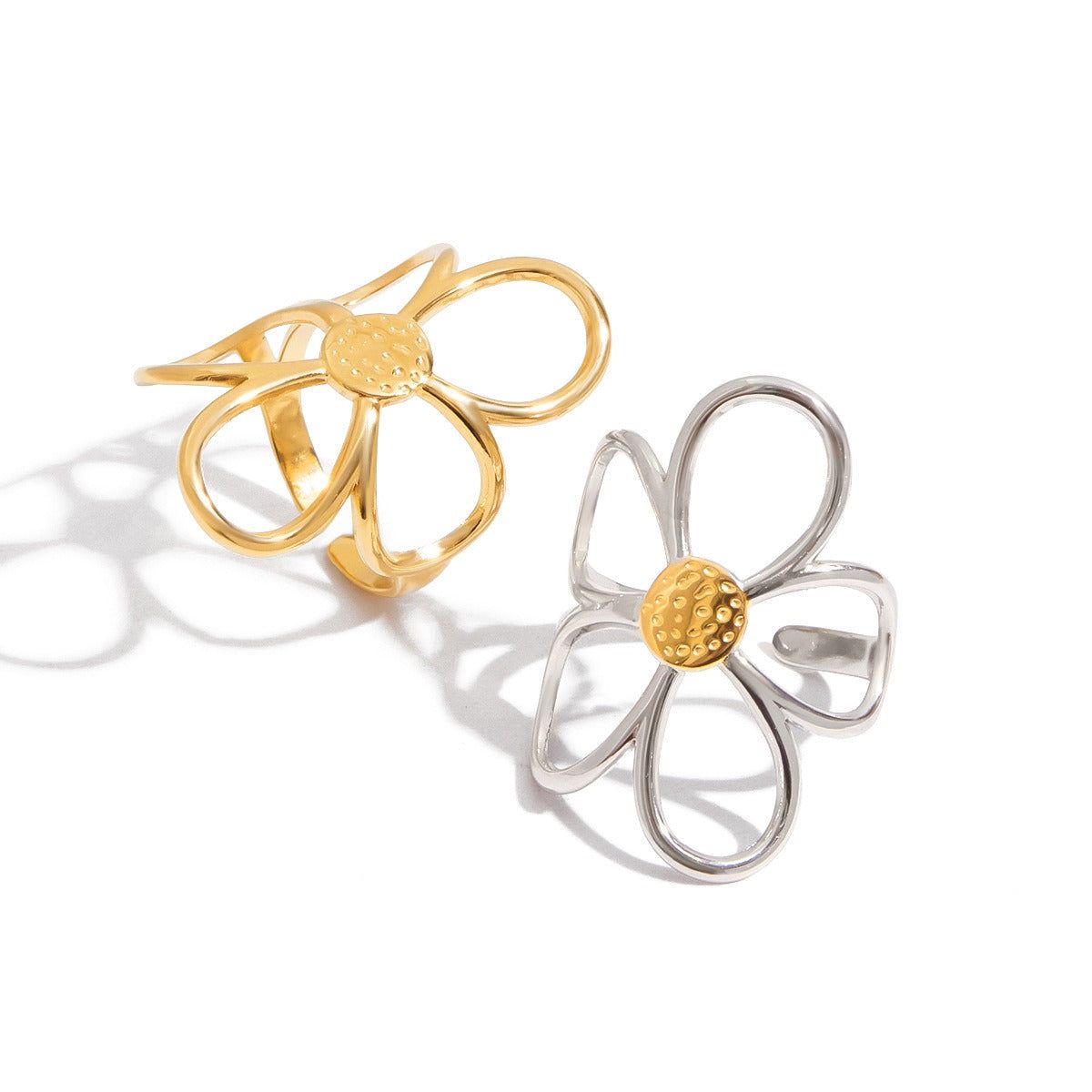 Un conjunto de dos anillos abiertos en forma de margarita en tonos dorado y plateado, hechos de acero inoxidable que no se empaña, mostrando el delicado diseño floral.