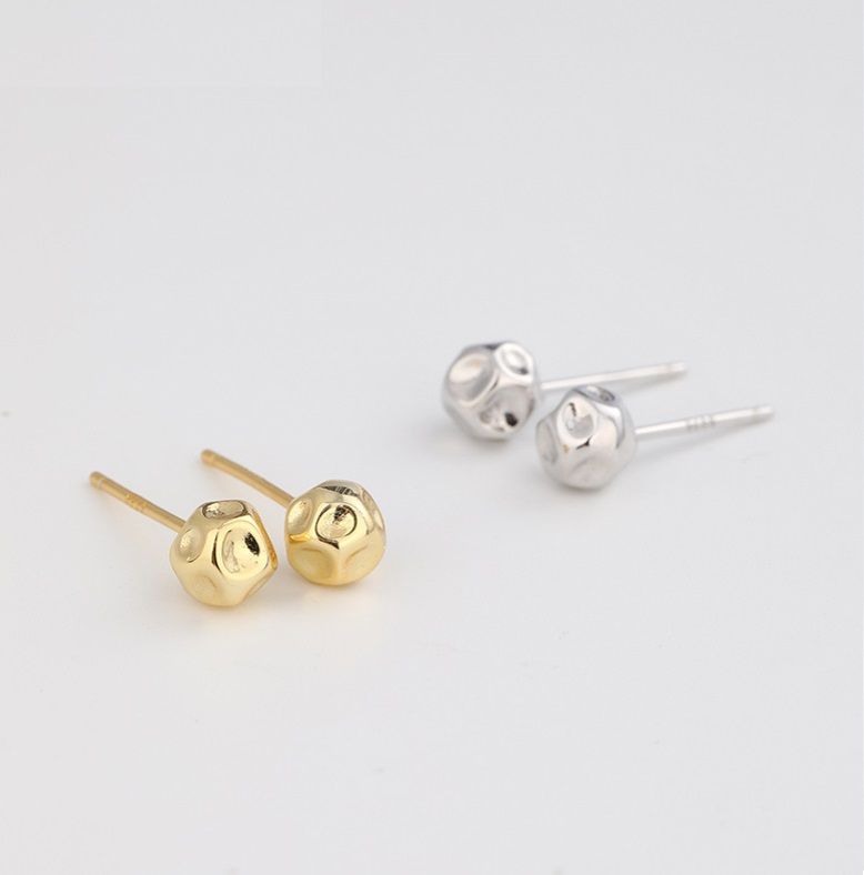 Un paio di orecchini a perno rotondi in argento sterling 925 con finitura martellata, esposti sia in argento che in oro su uno sfondo bianco.