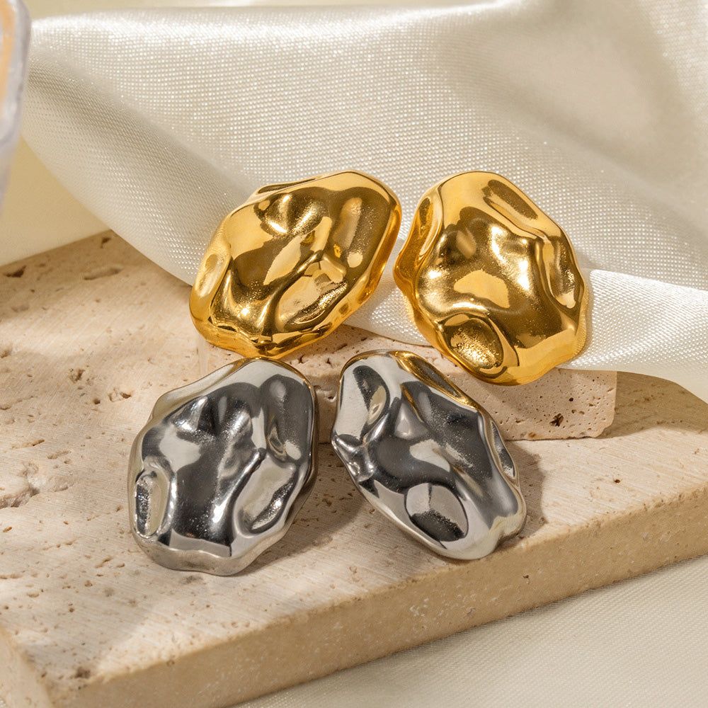 Un conjunto de pendientes irregulares de acero inoxidable martillado, mostrando acabados en oro y plata pulidos.