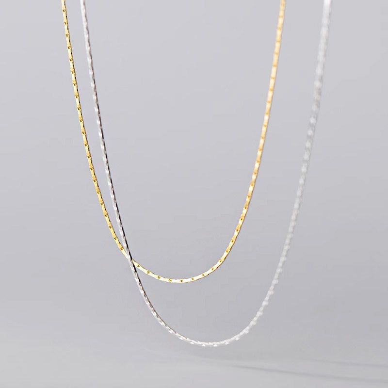 Un gros plan du produit des colliers en chaîne serpent super fins en argent sterling 925, mettant en avant les finitions en or et en argent ainsi que leur texture délicate.