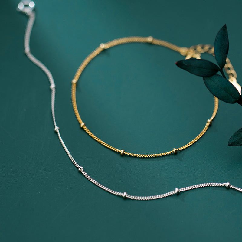 A set of 925 silver eternity fine beaded shimmer chain bracelets, showcasing both the elegant gold and classic silver options against a dark background.