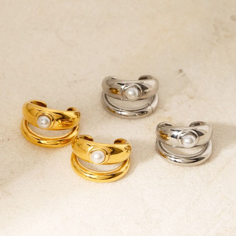 Un conjunto de aretes de clip con arete de perla de doble capa minimalista, mostrando tanto las variantes elegantes de acero inoxidable dorado como las clásicas plateadas.