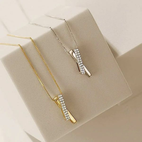 Un collar de cruz de plata esterlina 925 mostrado en acabados de plata y oro, adornado con brillantes piedras de circonita.