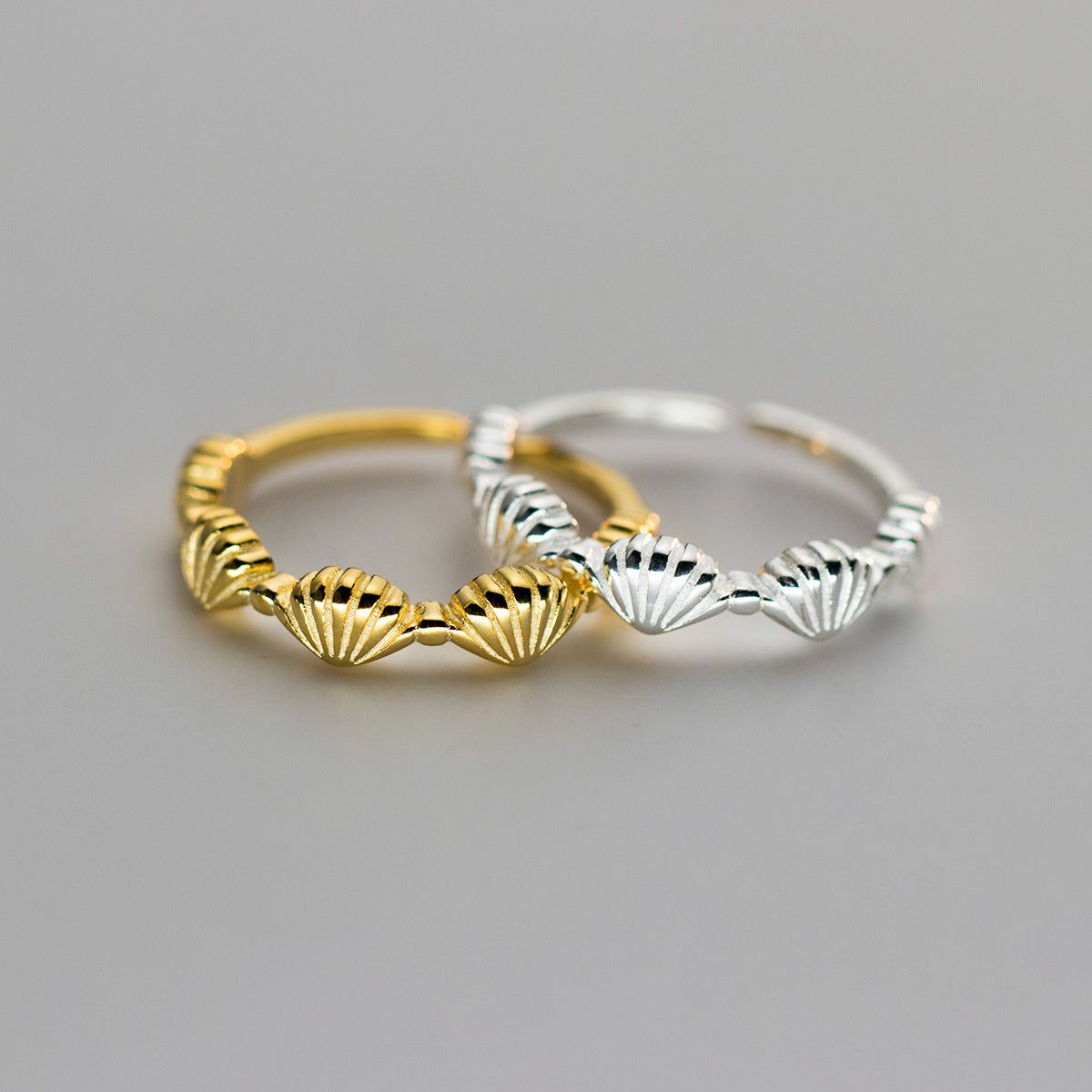 A stunning set of two 925 sterling silver rings with a seashell design, one plated in gold and the other in polished silver, showcasing the adjustable feature.