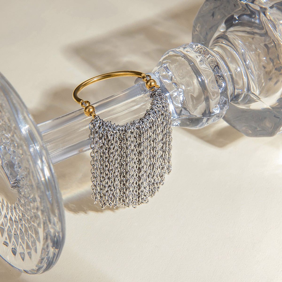 A close-up of the two-tone stainless steel tassel ring with a gold base and silver chain, part of a wholesale set for women.