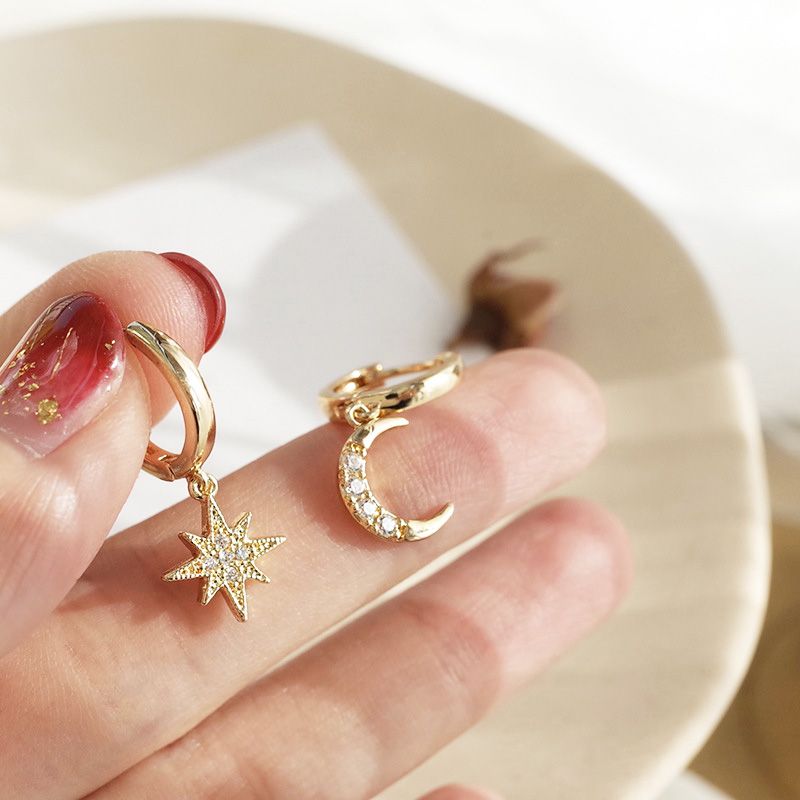 A pair of 925 sterling silver star and moon earrings in a gold finish, featuring sparkling cubic zirconia stones on the celestial charms.