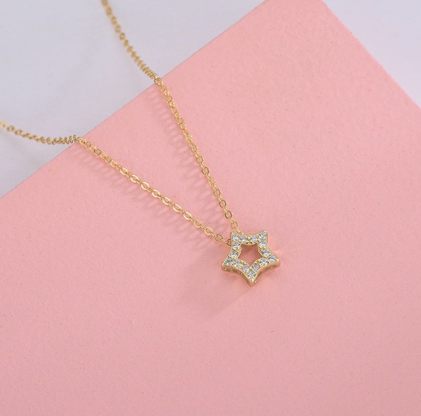 En detaljerad närbild av 925 Sterling Silver Stjärnhalsbandet, med en guldpläterad stjärnpendel som är prydd med briljanta vita kubiska zirkonia-stenar.