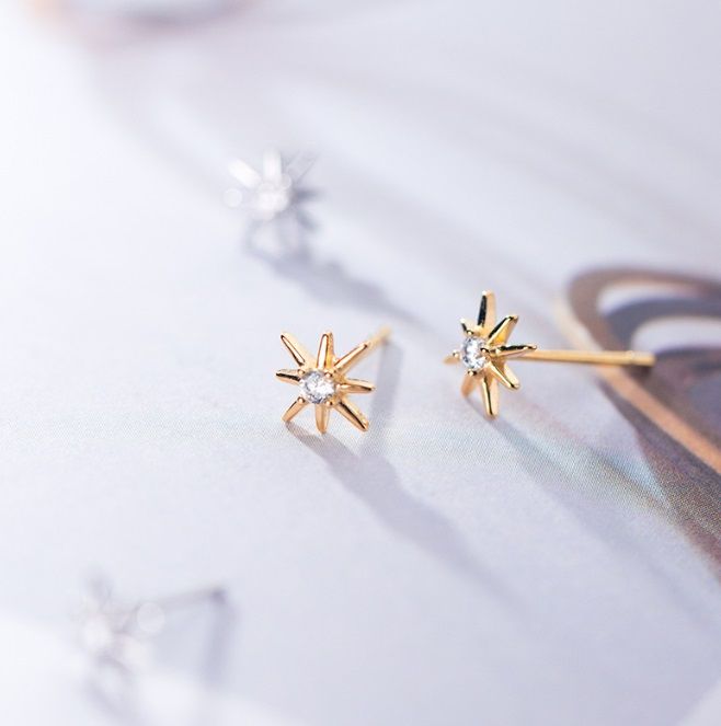 Un paio di orecchini Starburst in argento sterling 925 con una finitura dorata radiosa, caratterizzati da una pietra centrale in zirconia cubica scintillante.