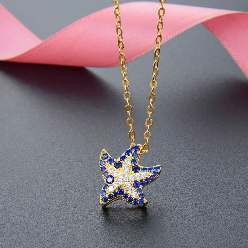 Een close-up van de 925 Sterling Zilver Goud Geplateerde Ocean Sapphire Zeester Hanger Ketting, die de ingewikkelde details van de blauwe en witte edelstenen op de gouden ketting toont.