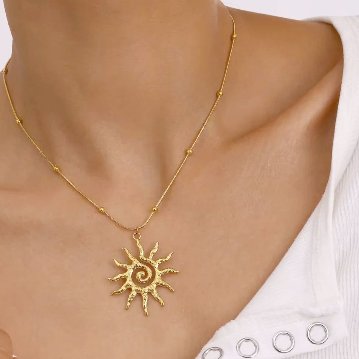 Un conjunto de cinco collares de acero inoxidable bañados en oro de 18k con colgantes de sol huecos, exhibidos sobre un fondo neutro para resaltar su diseño.
