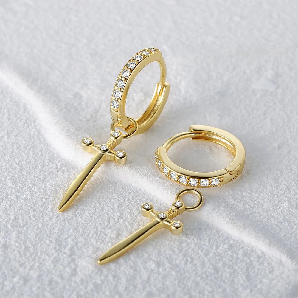 Un paio di orecchini a cerchio in argento sterling 925 placcati in oro, con un ciondolo a forma di spada pendente abbellito con pietre di zirconia scintillanti, su uno sfondo bianco pulito.