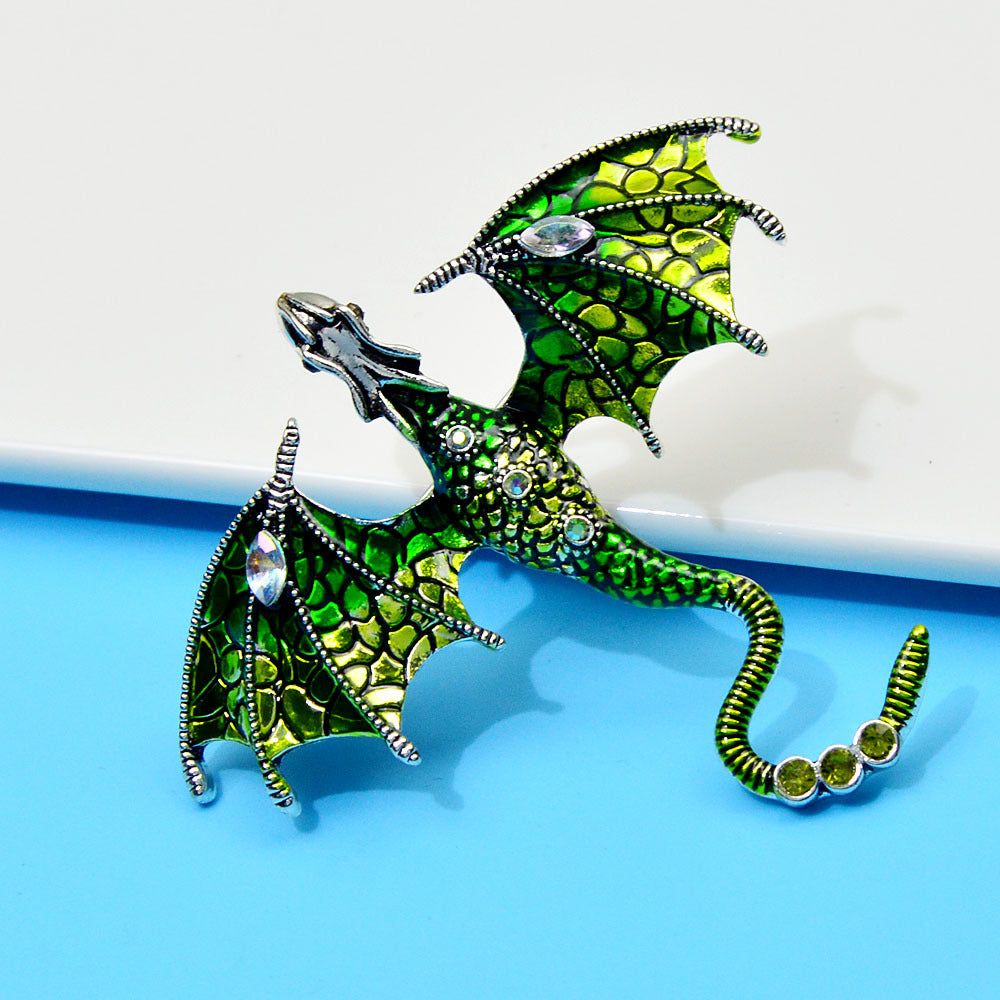 Eine Nahaufnahme der Emaille-bemalten Strass-Drachenbrosche, die ihr kompliziertes grünes Mosaikdesign und funkelnde Edelsteinverzierungen zeigt.